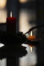 Two candles stand on a table in front of a window at dusk and create a Christmas atmosphere,
