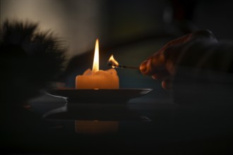 Hand still holding a burning match after a yellow candle is lit, Christmas atmosphere, Finland