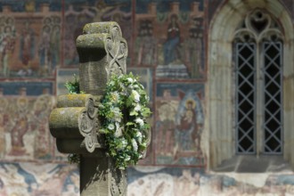 Artificial flower wreath on a stone cross in front of the Romanian Orthodox Women's Monastery,