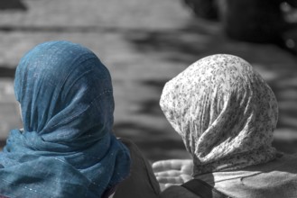 Two woman wearing headscarves talking on a bench, black and white, Paris, France