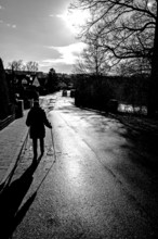 Aetere woman with sticks running on rain-wet road in backlight, black and white, Eckental, Middle