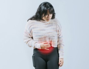 Sore Asian woman with digestive problems. Female person holding stomach with digestive problems