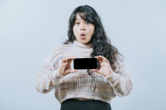 Surprised asian woman showing phone screen isolated. Beautiful asian girl showing promotion on