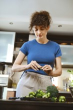 Woman is tearing up broccoli with fingers in a kitchen. The countertop has fresh broccoli. The