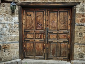 Old wooden door with graffiti on a stone wall, next to it an old lamp, Antalya Turkey