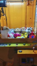 Automatic grappling machine full of colorful stuffed animals in a yellow case, Batumi, Georgia