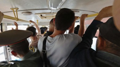 People in a tight bus interior holding on while driving, Armenia