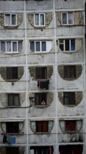 Dilapidated residential building with open windows and people in a simple environment, Tbilisi,