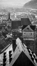 Black and white photo of a town with church tower and historic buildings, view over the roofs of