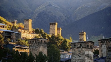 Village with historic towers and mountains in the background at sunset, Mestia, Georgia