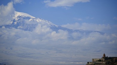 Snow-capped mountains and cloudy sky with a small monastery at the base, Khor Virap with Ararat in