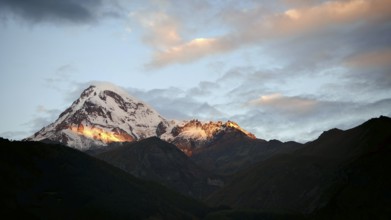 Sunset over snowy mountain with dramatic sky, Kazbek, Stepantsminda, Georgia