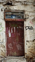 Old red door with graffiti in a weathered building, abandoned atmosphere, Ohrid, North Macedonia