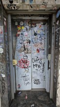 Elevator doors covered with graffiti and stickers in an urban setting, Prizren, Kosovo