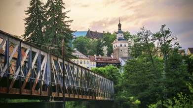 Scenic city view with bridge, historic buildings and trees at dusk, Loket, Czech Republic