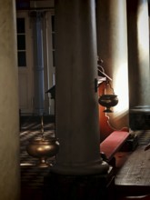 A quiet church interior with tall pillars and a hanging incense barrel in a play of light,