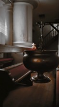 An incense barrel hangs in a quietly lit row of church benches, Frankenwald