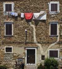 Rustic stone wall with hanging clothes and closed shutters, Koper, Slovenia