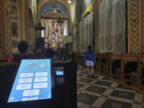Church interior with decorative altar, visitors and donation machine