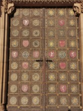 Large, richly decorated wooden door with golden and coloured coats of arms