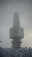 Mighty tower, surrounded by snow and fog, towering into the cloudy sky, Baköfele on the Schneeberg,