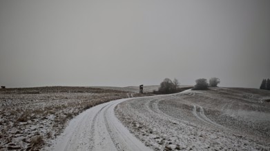 Snowy field with a winding path and grey sky, Franconian Forest nature park Park