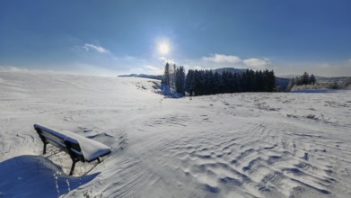Snowy field with bench and sun in a clear sky, Fichtelgebirge, Bavaria