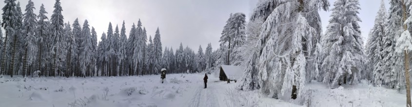 Snowy forest with hut and two people under cloudy sky, Rennsteig, Thuringian Forest