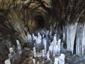 Ice cave with ice stalactites, icicles on rocky walls create a cold, mystical atmosphere,