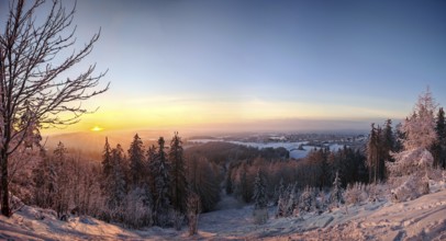 Panoramic view of a snowy winter landscape with village and sunset