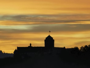 Silhouette of a castle against an orange sky at sunset