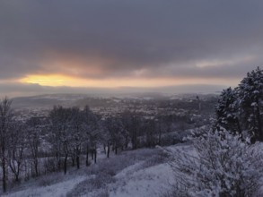 Snowy landscape with view of a village at sunset, view over Kronach in the Franconian Forest