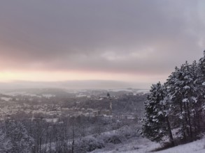 Snowy hills with a view of a village at sunset, view of Rosenberg Fortress and the town of Kronach,