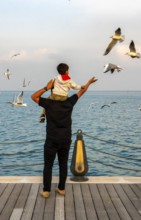 Mina District across from the cruise terminal, locals and tourists feed the seagulls, Doha, United