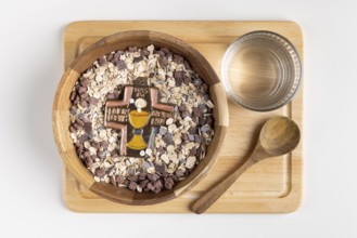 Wooden bowl with cereal and a cross on a wooden board with water, fasting