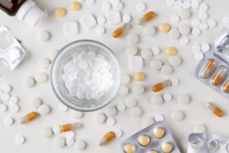 Scattered white tablets and a glass of water on a table