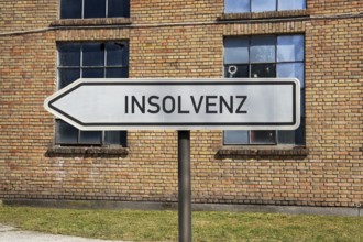 (Photo montage) Directional arrows with the inscription BANKRUPTCY in front of an old industrial