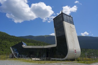 Modern building with futuristic design in front of a picturesque mountain landscape, airport