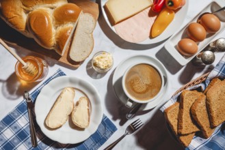 Breakfast with toast, sliced stollen, honey, cheese, ham, coffee, butter, bell pepper and eggs