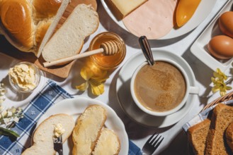 Breakfast, stollen with butter and honey, surrounded by cheese, ham, coffee, peppers and eggs
