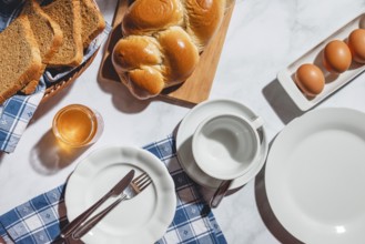 Breakfast items such as toast, stollen, eggs and honey on a white table