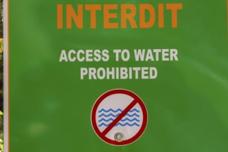 Posted bilingual French and English language warning Access to Water Prohibited in white and orange
