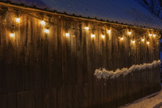 Illuminated old weathered wood plank cladded barn decorated with old industrial style string lights