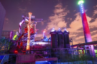 Colourful lighting on industrial buildings with visible chimney, Landschaftspark Duisburg Nord,