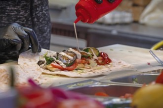 Preparation of falafel with vegetables and mayonnaise at a stand in the pedestrian zone, Nuremberg,