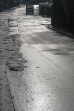 Remains of snow on rain-wet road against light, Eckental, Middle Franconia, Bavaria, Germany