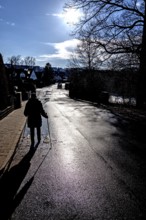 Aetere woman with sticks running on rain-wet road, back light, Eckental, Middle Franconia, Bavaria,