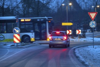 Car and bus at roundabout during night snow flurries, Eckental, Middle Franconia, Bavaria, Germany