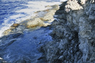 Coast with rocky cliffs and rough sea in bright sunlight, Playa Blanca Lanzarote