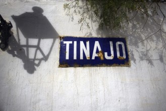 Blue sign with the words' Tinajo 'on a white wall shaded by a lantern, Tinajo Lanzarote